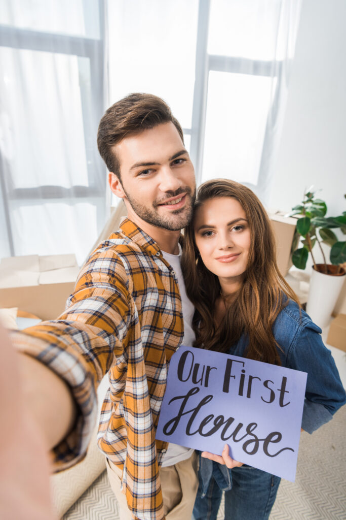 couple with sign that says our first house